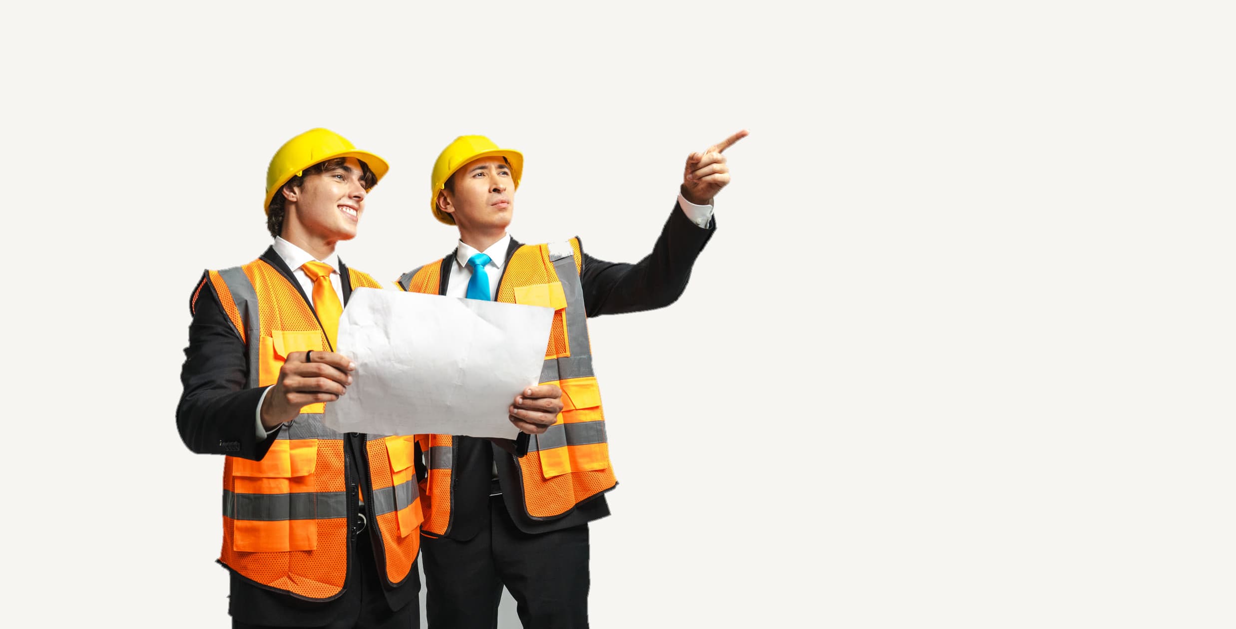 KingChris and Gianni Sirgy in hard hats and safety vests over their suits, holding a blueprint while one of them points ahead.